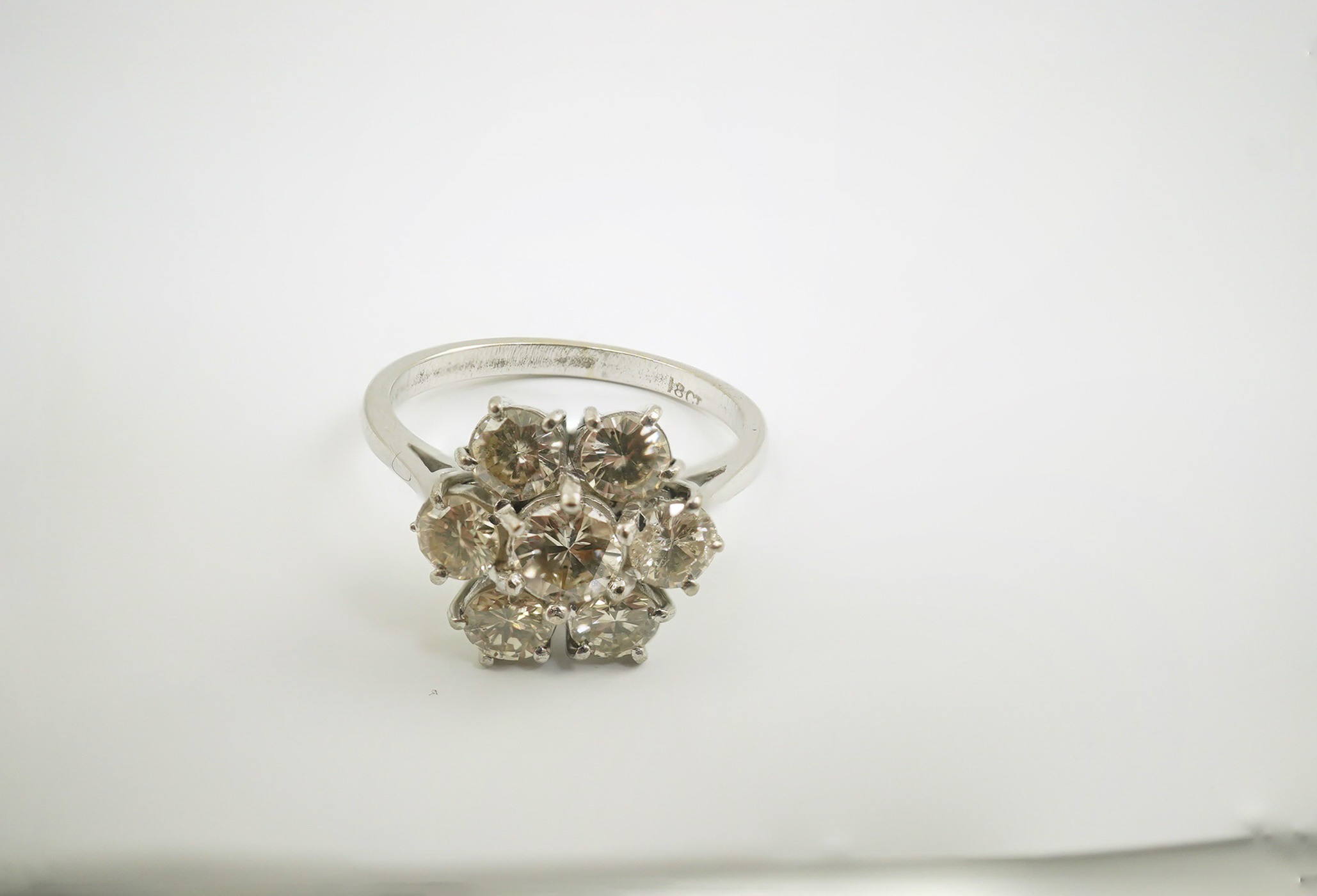 An 18ct white gold and seven stone diamond set flower head cluster ring